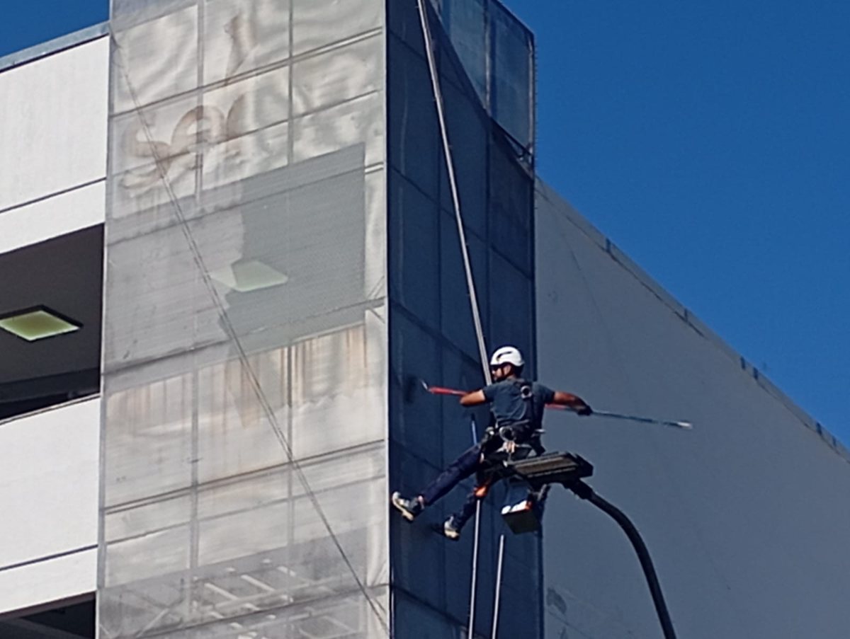 Profissional da Realiza Engenharia em trabalho de altura com cordas na fachada de um edifício